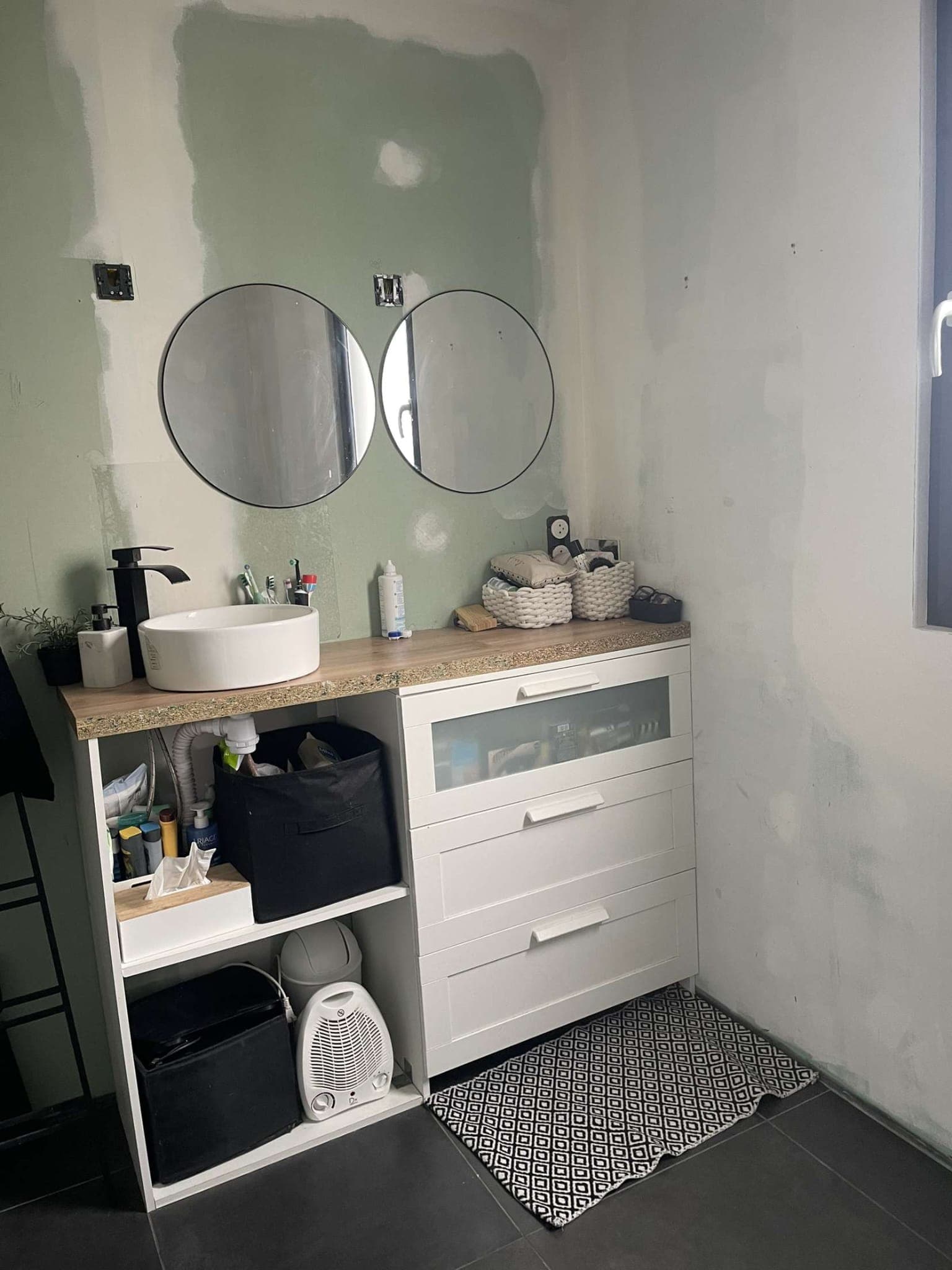 L'ancien meuble vasque, son plan stratifié et ses deux miroirs ronds.