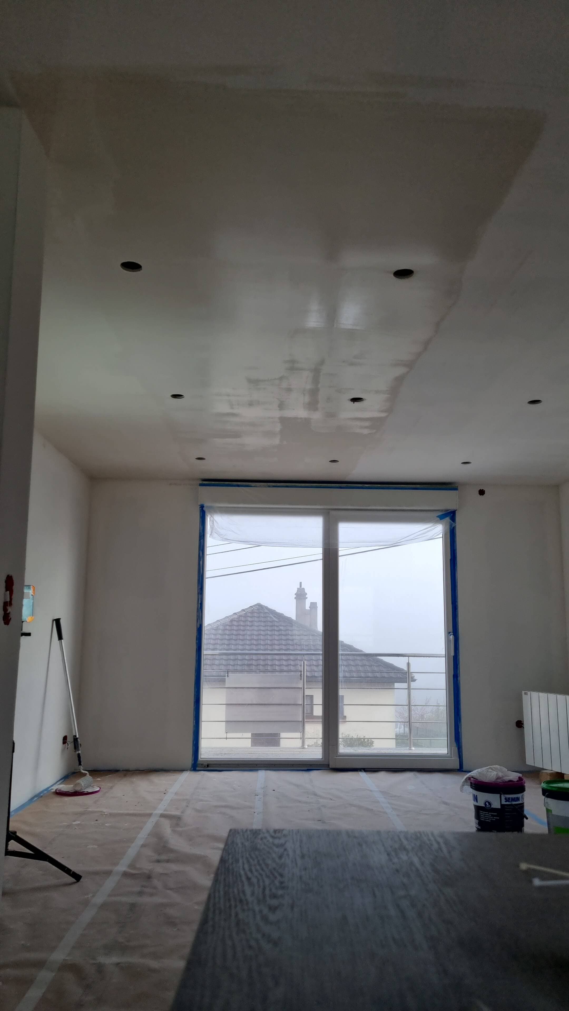 Murs et plafond ratissés, menuiseries masquées avant la mise en peinture